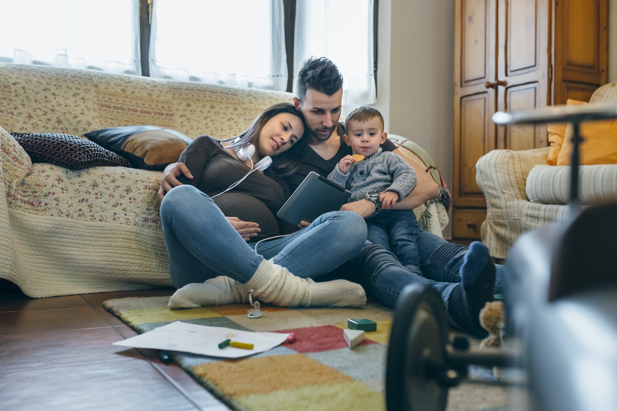 Family with child and pregnant mother looking tablet